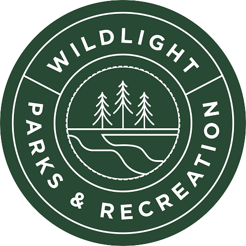Circular green logo with "Wildlight Parks & Recreation" text, featuring three pine trees and a river inside a central circle, representing the natural beauty of the Wildlight Yulee Florida community.