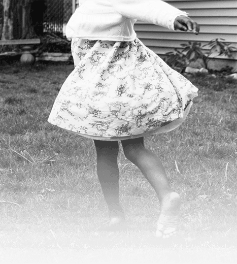Black and white photo of girl spinning in a dress.