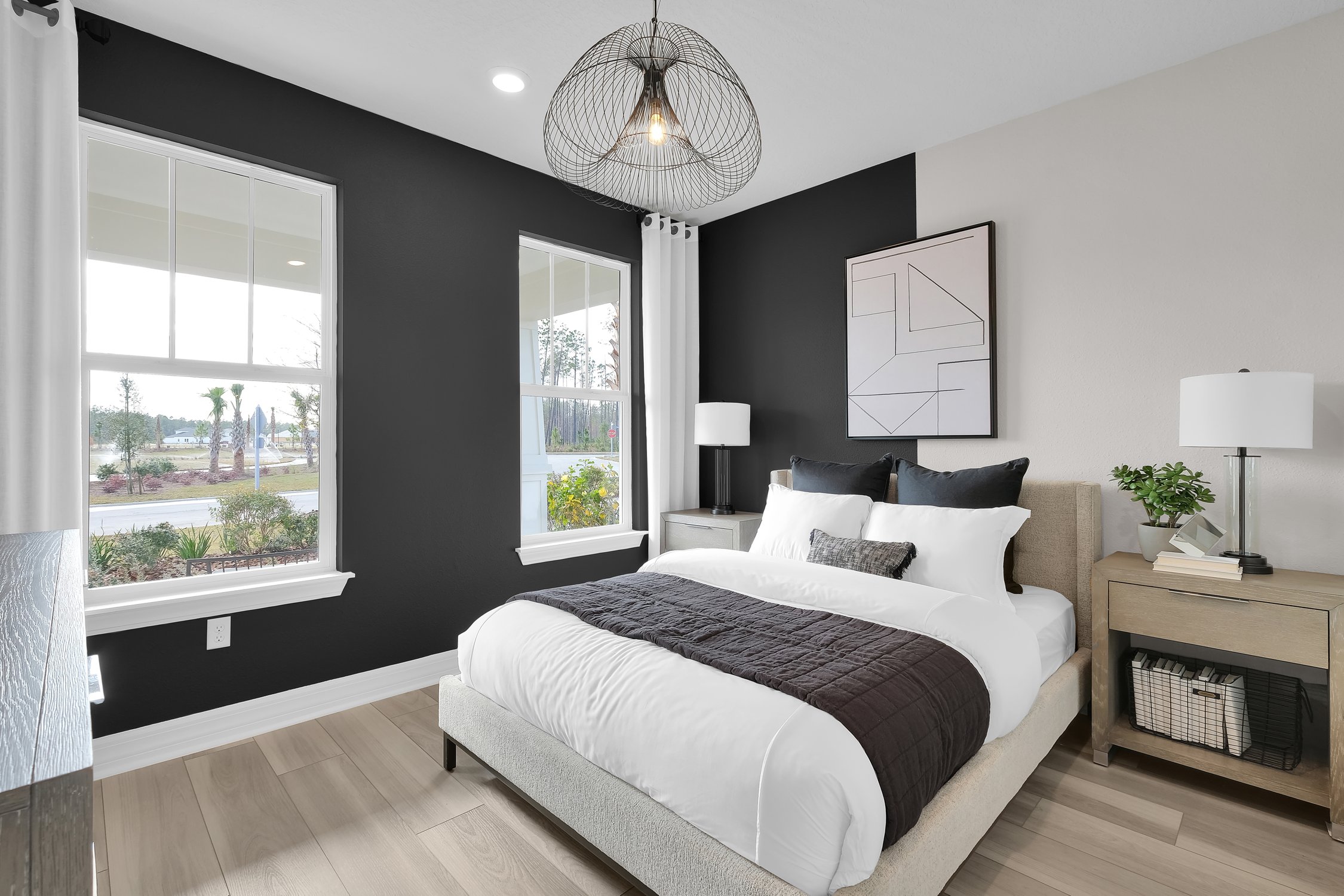 Pulte Homes Wildlight bedroom with two large windows, queen bed, two night stands and a dark blue accent wall.