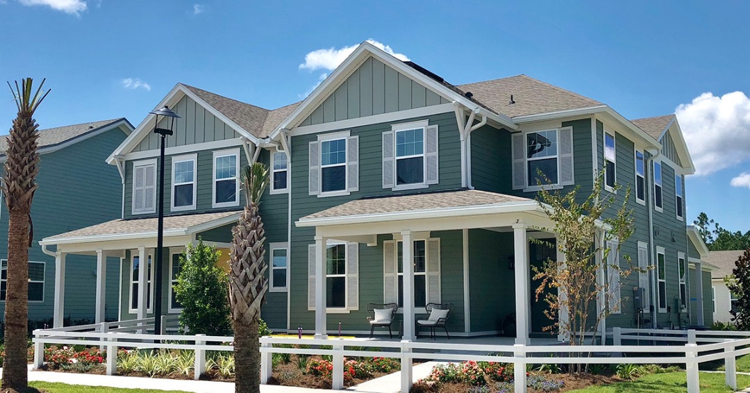 Dostie Homes Wildlight townhomes exterior painted in green with white trim and large front porches.