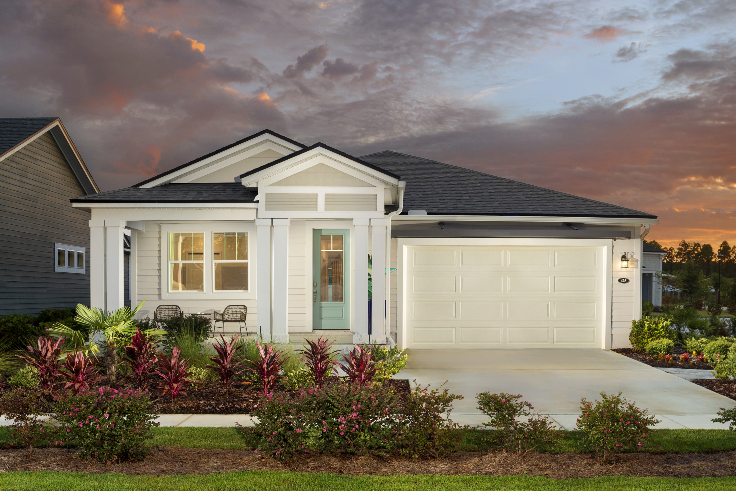 Mattamy Homes Wildlight single-story home at night with cream exterior, white trim and teal front door.