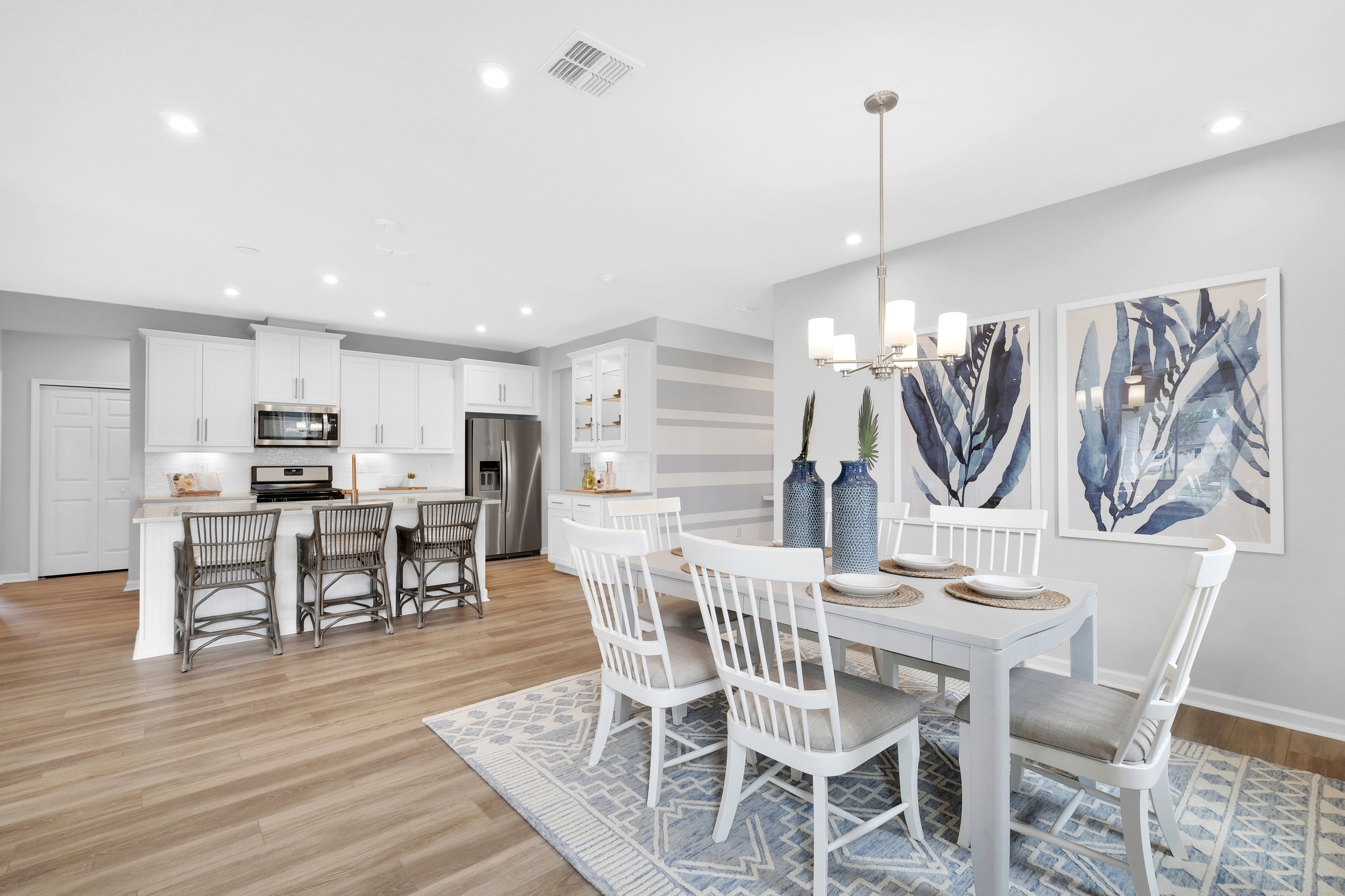 Mattamy Homes Wildlight open concept kitchen, living and dining room. White kitchen with island, wood floors and large dining table.