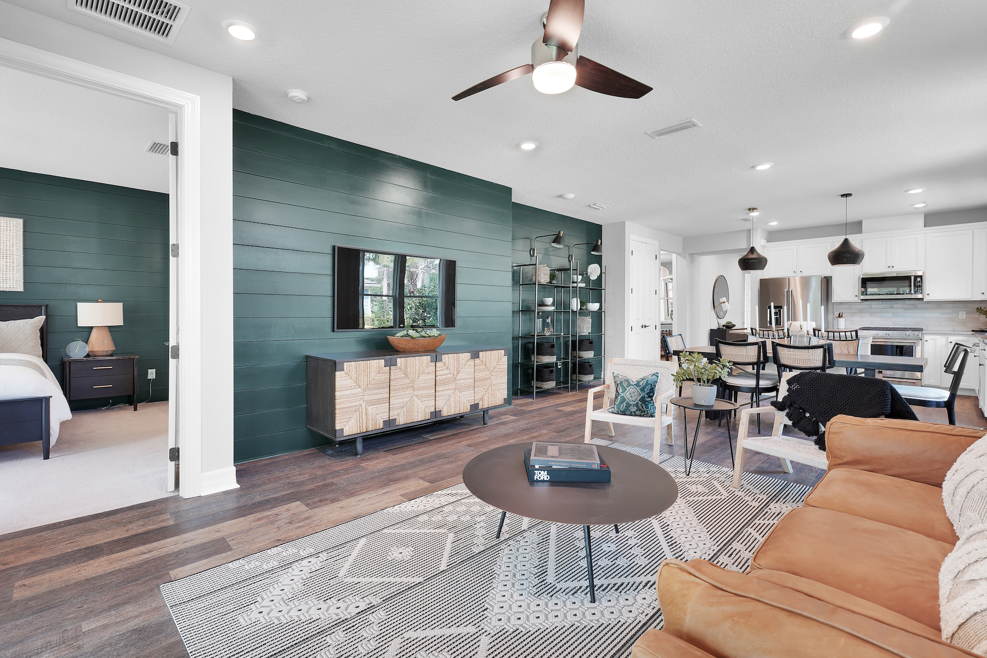 Del Webb Wildlight open concept white kitchen and living room with green shiplap accent wall.