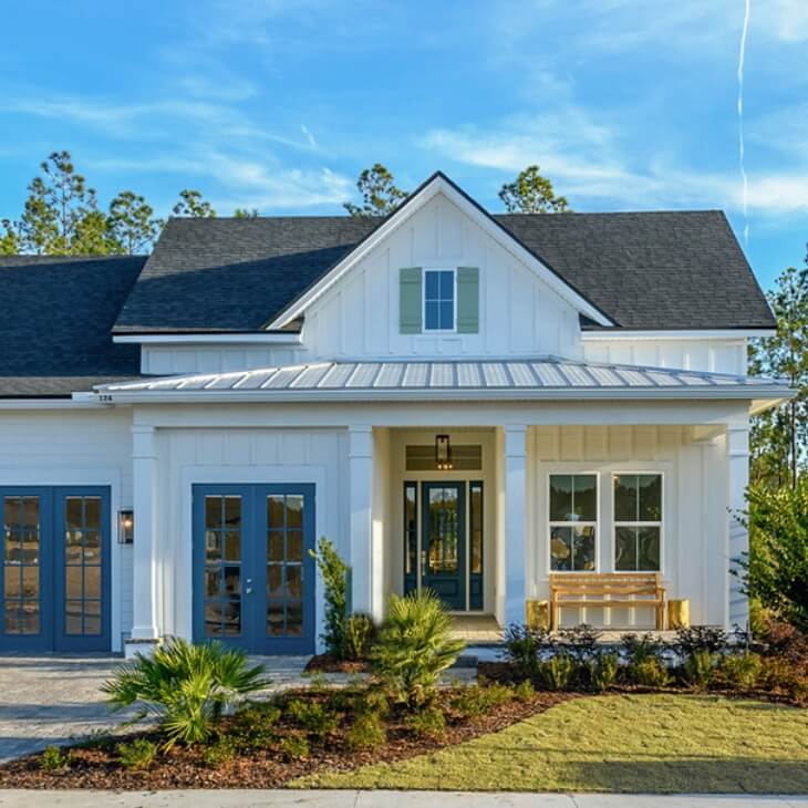 White two-story model home with blue and yellow trim and accents with a spacious front porch.