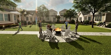 Group of people enjoying a fire surrounded by adirondack chairs and green grass in front of new for-lease single-family homes in Wildlight.