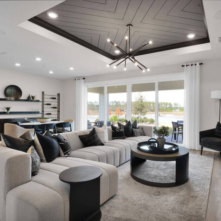 Modern living room with large couch and black coved ceiling.