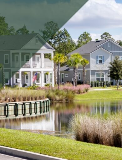 A small pond with three, two story homes across the water and trees behind the houses.