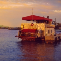 A river cruise boat with a red cover in water as the sun sunsets with Amelia River Cruises.