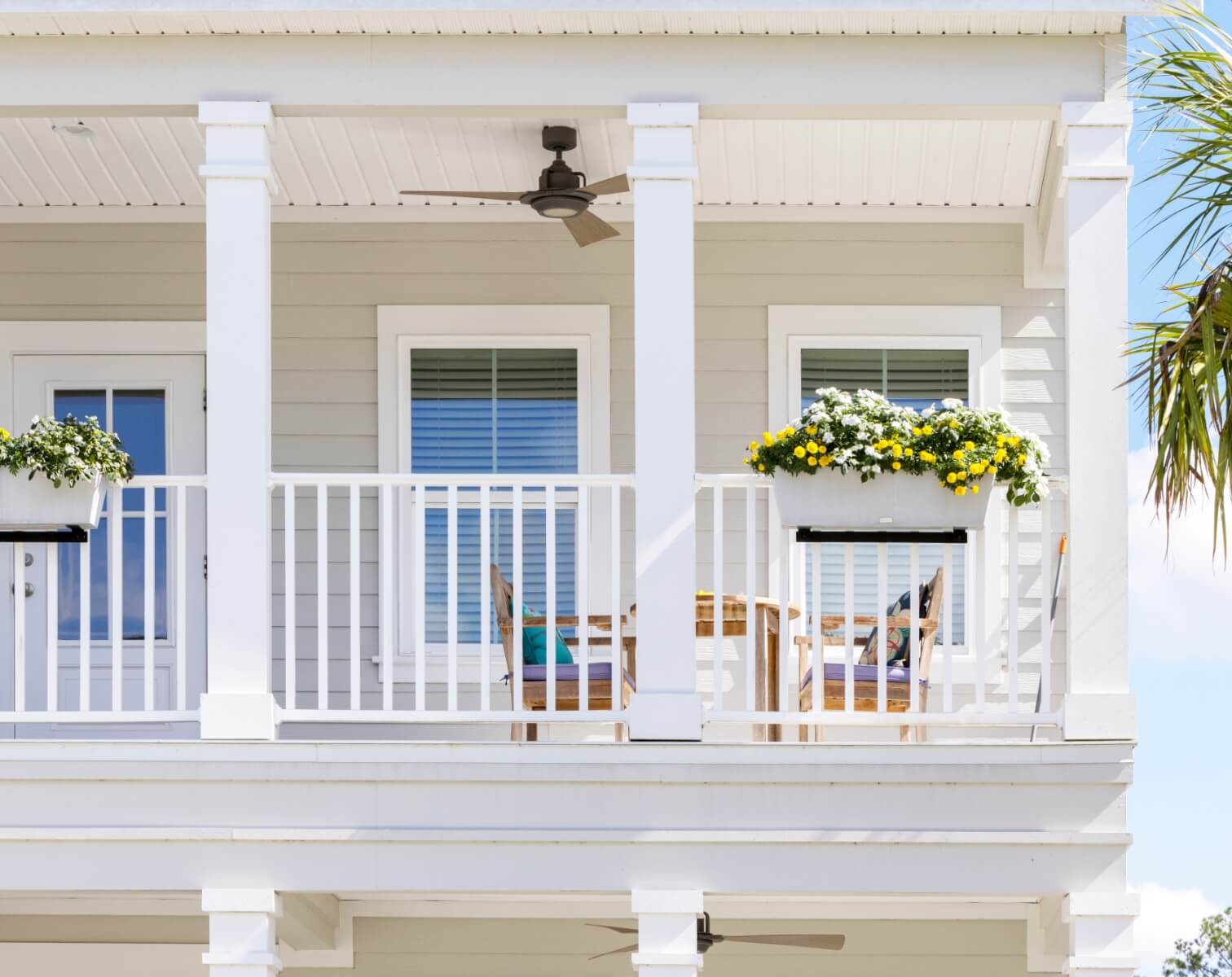 Second-story balcony of a Florida Lowcountry home in Wildlight with flower box, three windows and bistro set.