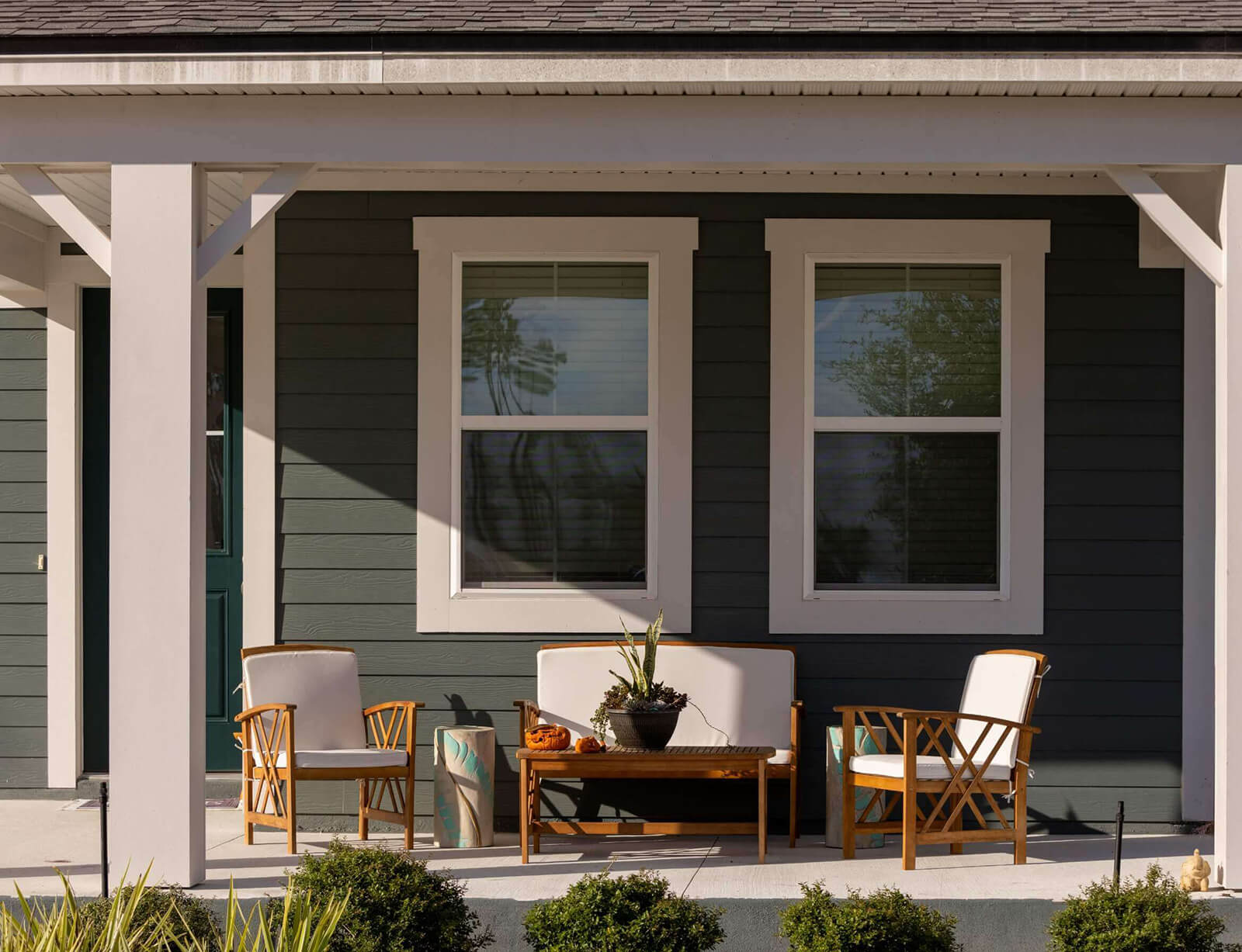 The front porch of a home with a wooden table and chairs.