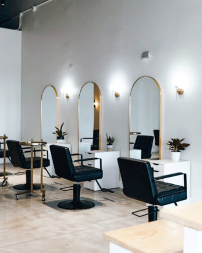 A hair salon with black chairs and mirrors.