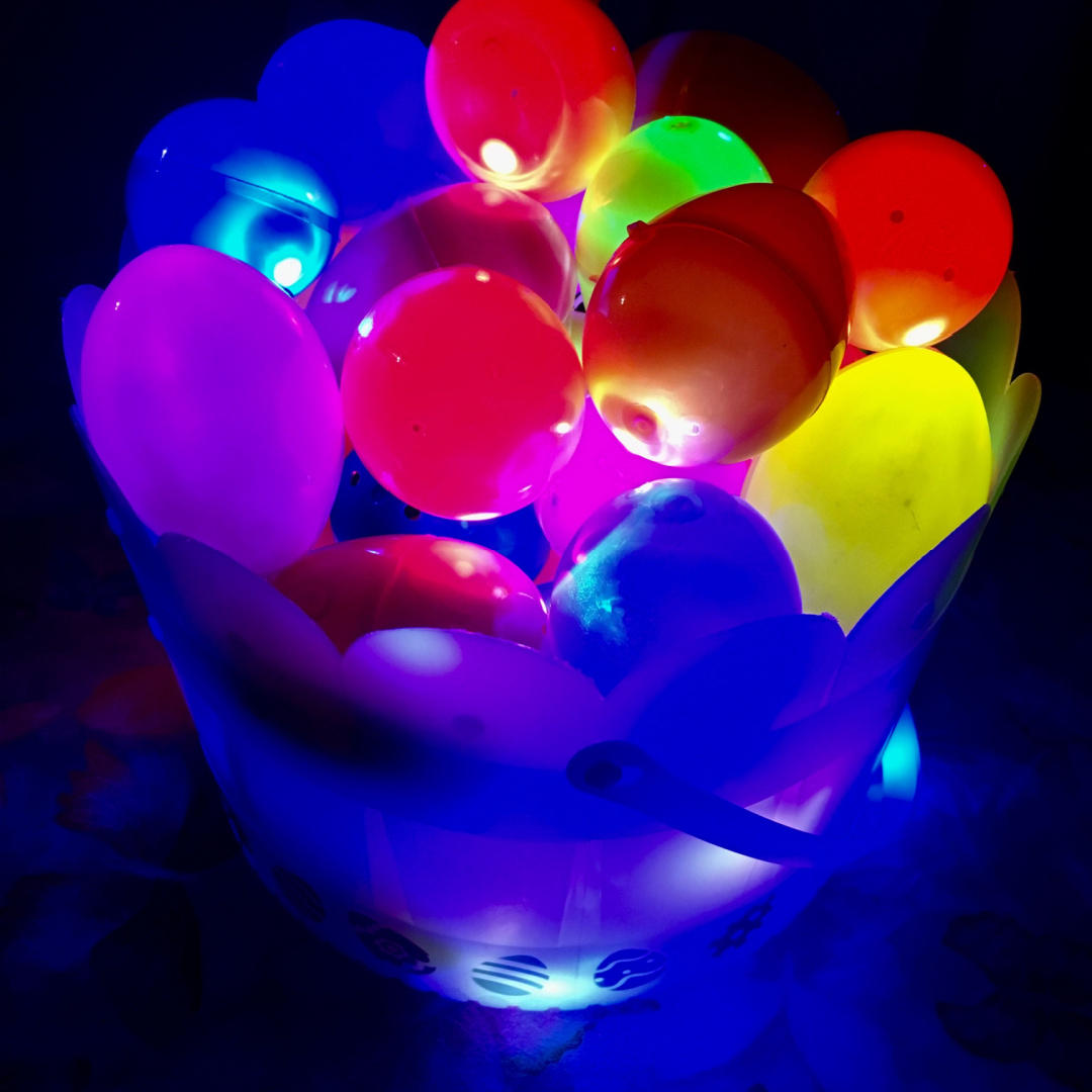 Colorful balloons in a bucket on a dark table.