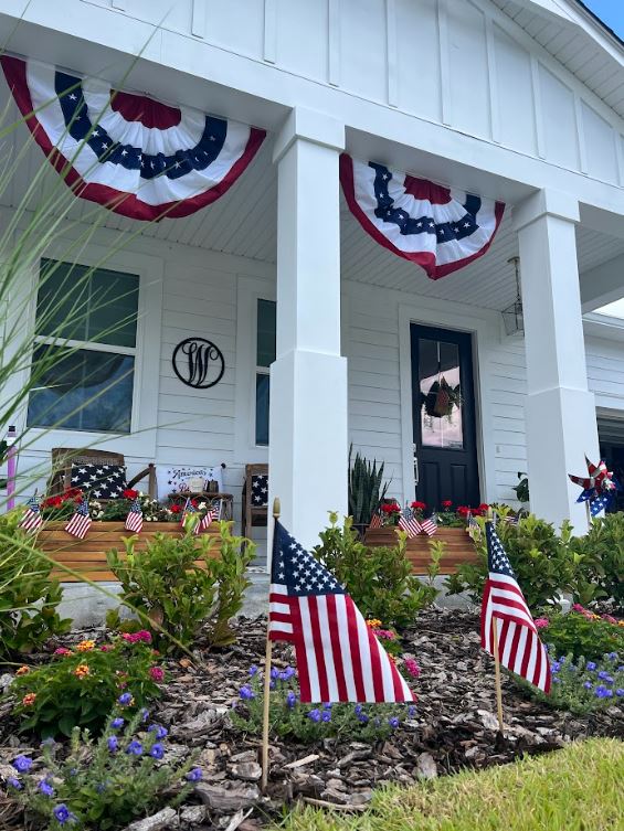 A home with american flags on the front porch.
