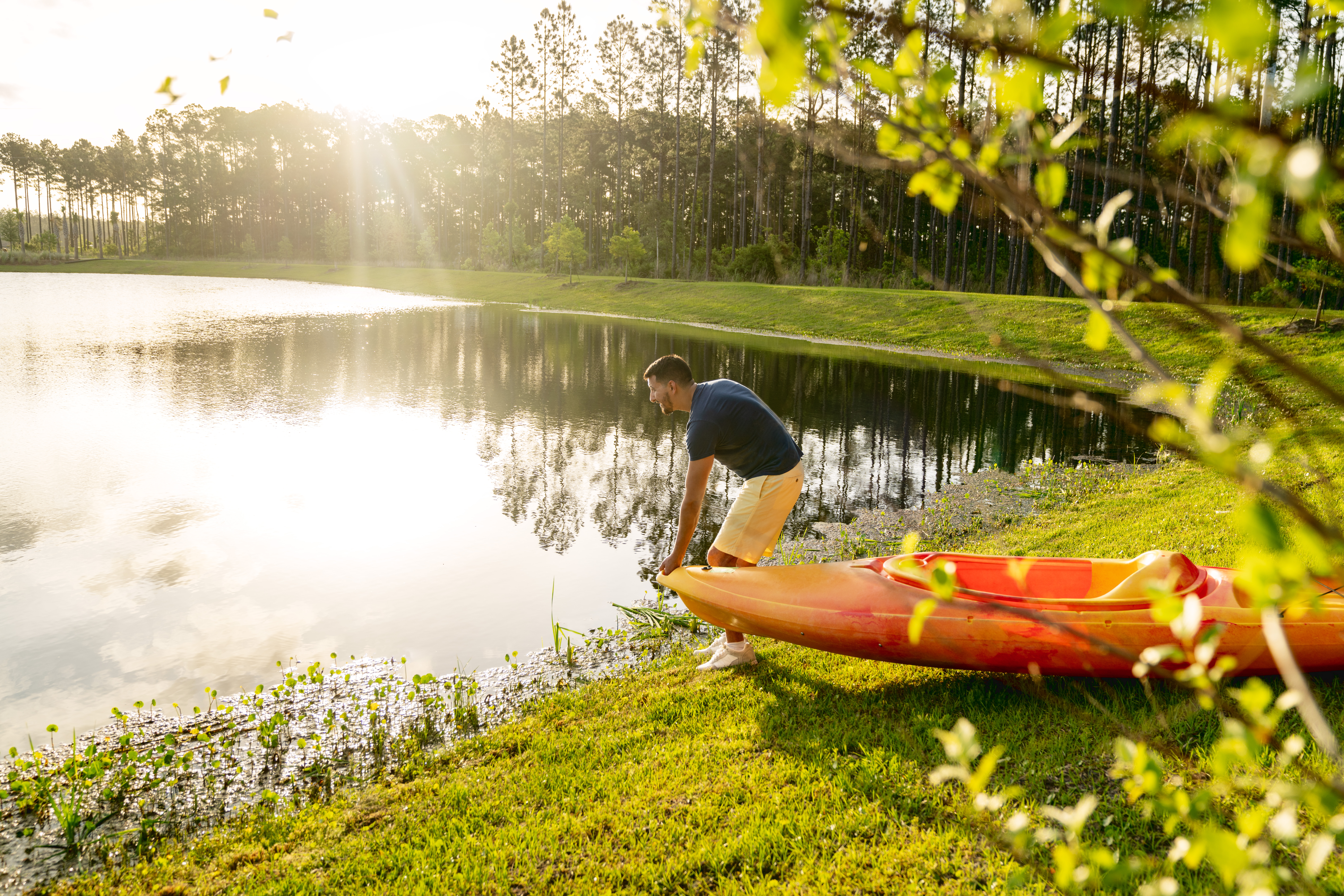 Man putting kayak in pond.