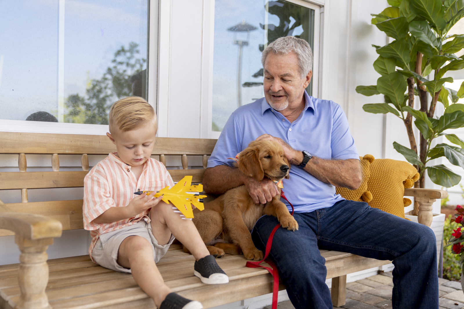 An older man and a young boy sitting on a bench with a puppy.