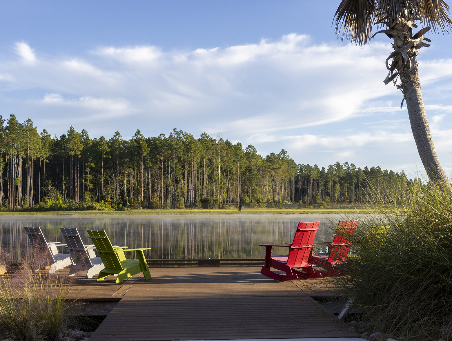 Five Adirondack chairs sit on dock overlooking pond in Wildlight.