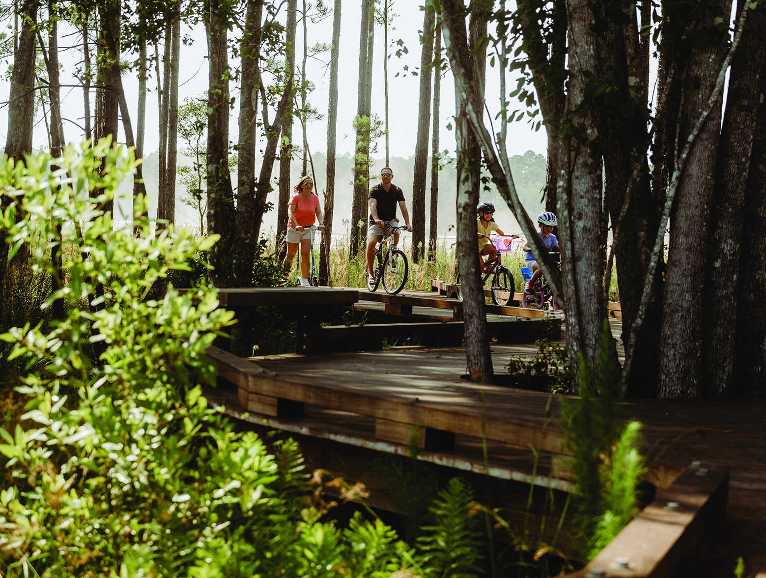 Family rides bikes and scooters through Wildlight boardwalks.