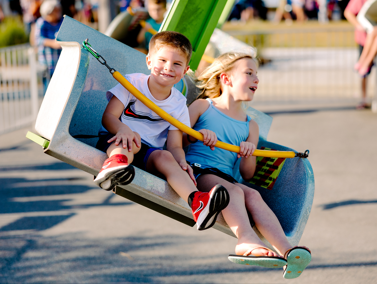 Two kids ride on carnival swing ride at Wildlight event.