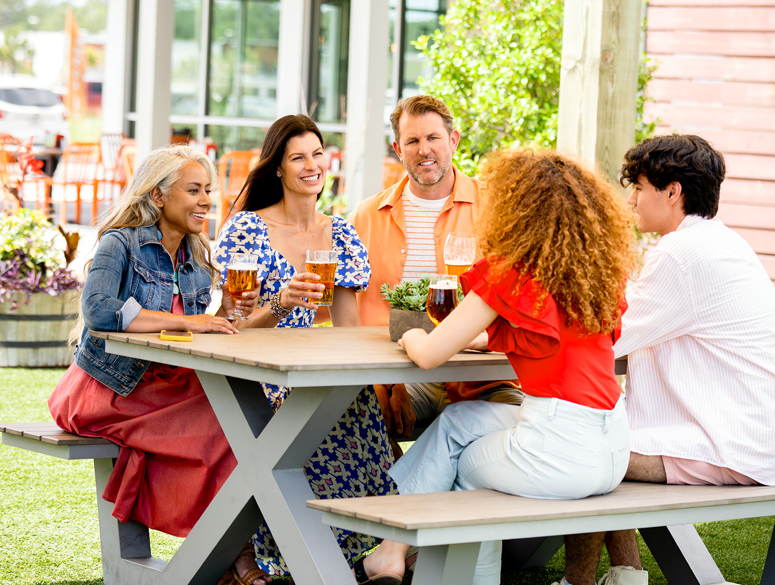Five people gather at a table and enjoy beers