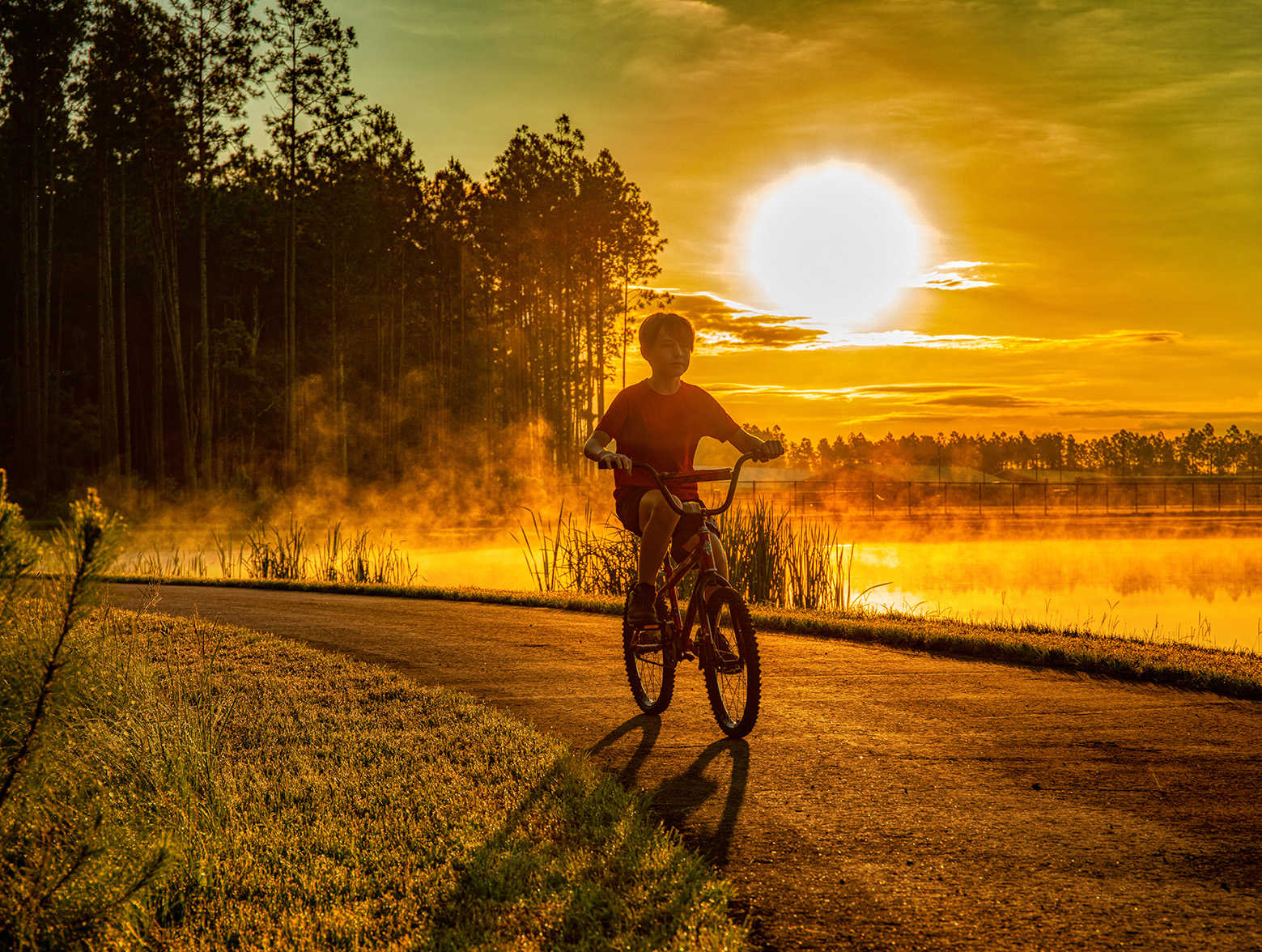 Boy rides bike through Wildlight at sunset.