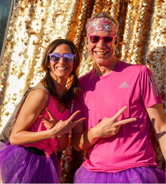 A man and woman in pink tutu pose for a photo.