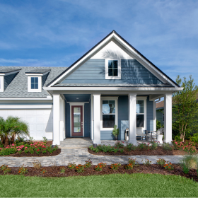 Charming single-story blue house with white trim, a covered front porch, and a landscaped yard with flowers and shrubs—perfect for those seeking homes in Nassau County Florida under a partly cloudy sky.