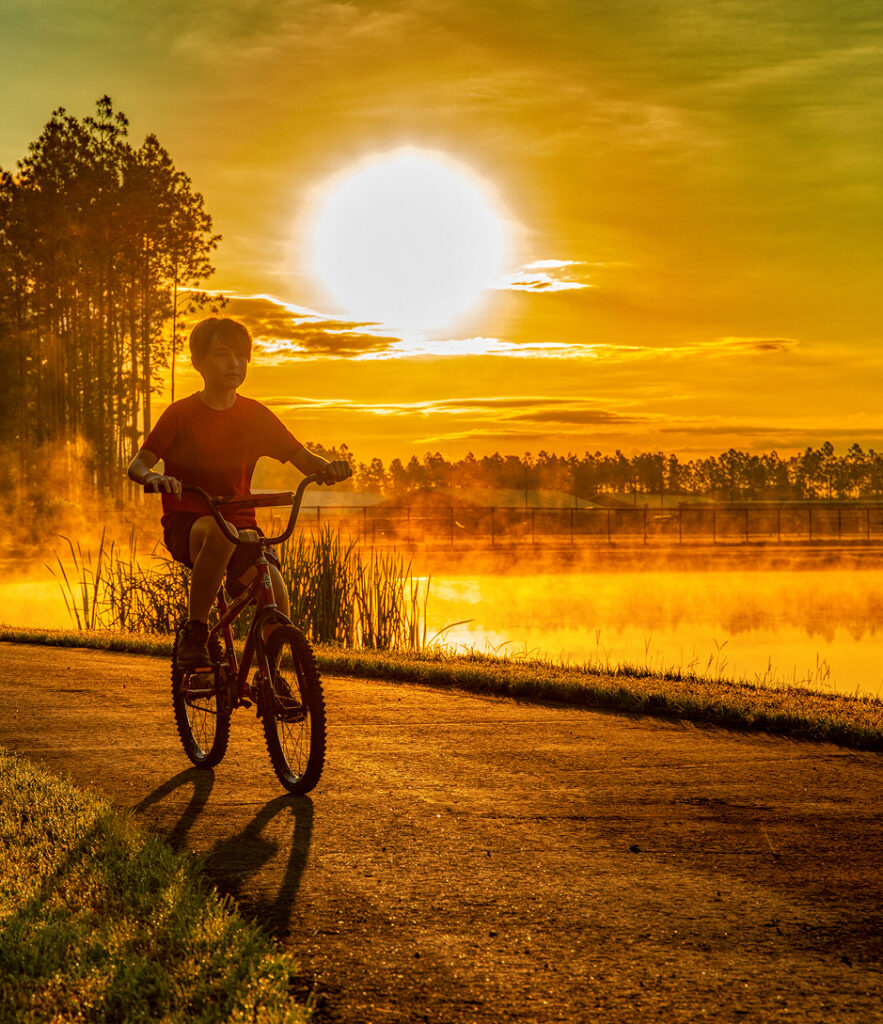 A boy riding his bicycle at dusk