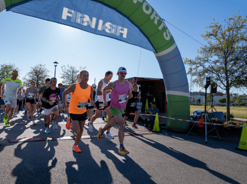 A group of runners starts a race under an inflatable archway labeled "FINISH" on a sunny day in the vibrant Wildlight Florida community, surrounded by the welcoming spirit of homes in Nassau County, Florida.