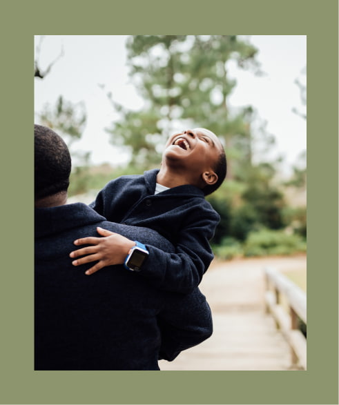 Boy laughing being carried by father