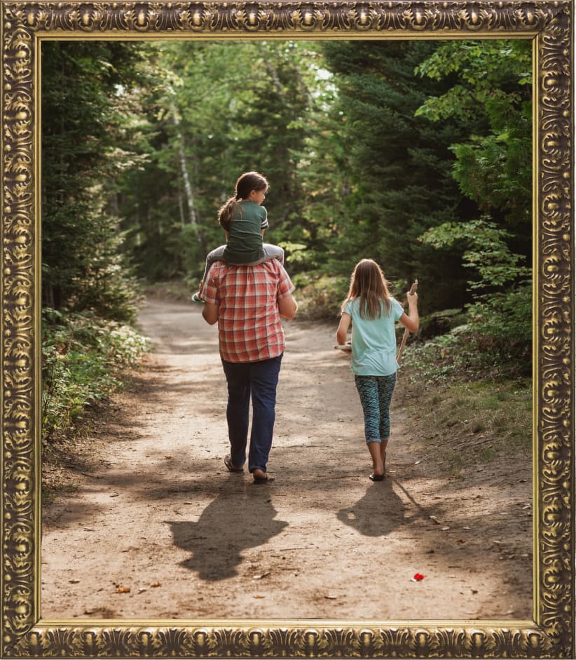 Family walking along woods path framed