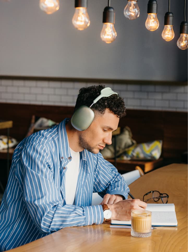 Man writing in book in coffee shop