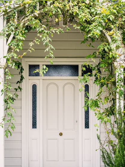 Front door of house with ivy on trelis