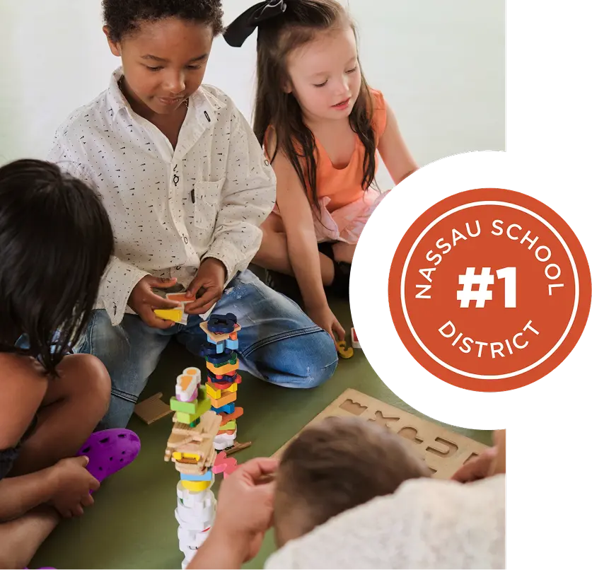 Four young children are playing with stacking blocks and puzzles on the floor, next to a badge reading "#1 Nassau School District," showcasing the family-friendly spirit of the Wildlight Yulee Florida community.