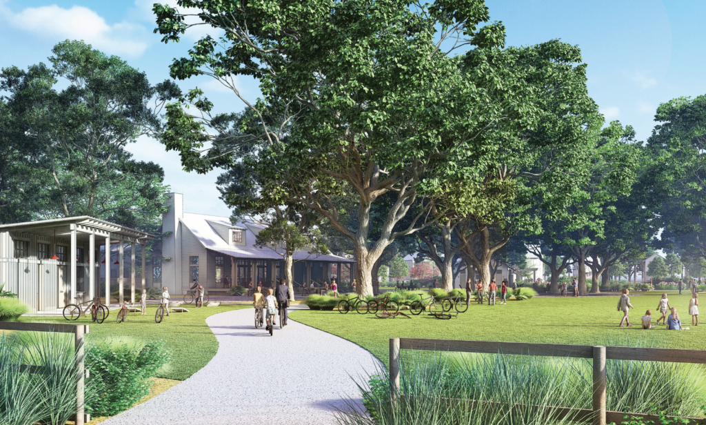 A paved path winds through a grassy park with large trees in Wildlight Florida, where people walk and cycle under the sun and new homes in Wildlight FL rise in the background.