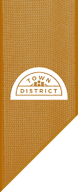 Brown textured banner with a white semicircle label reading "TOWN DISTRICT" in capital letters. The angled lower right corner adds style, reflecting the vibrant Wildlight Yulee Florida community and its inviting new homes in Wildlight FL.