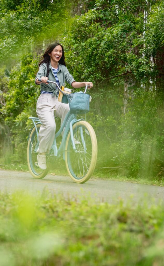 Woman riding bicycle along a river path