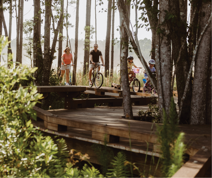 Family riding bicycles along a wooded trail