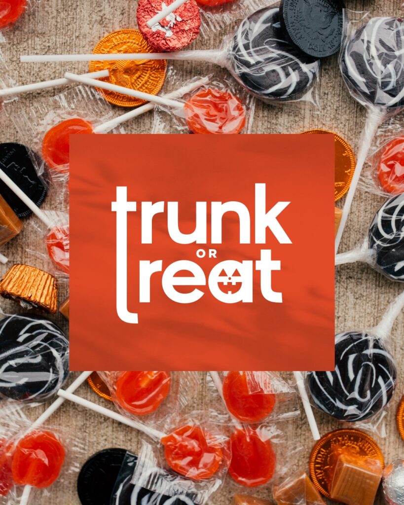 Assorted Halloween candies scattered on a surface with an orange sign in the center that says "trunk or treat" invite the Wildlight Yulee Florida community to celebrate spooky fun in the heart of beautiful new homes in Wildlight FL.