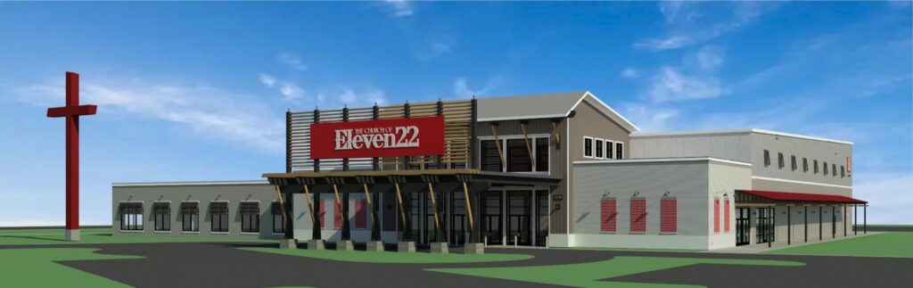 A modern church building with a large red cross and a sign reading "The Church of Eleven22" stands proudly in the Wildlight Yulee Florida community, set against a blue sky.