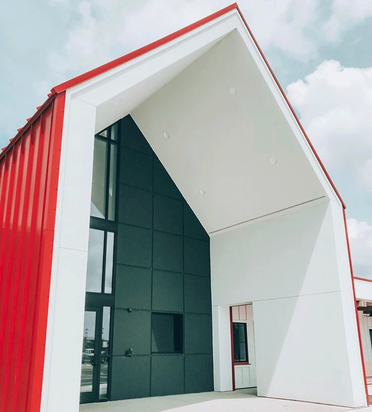 Modern building with a bold red and white geometric facade, featuring a large angled overhang and black-framed glass entrance—an eye-catching addition to new homes in Wildlight FL.
