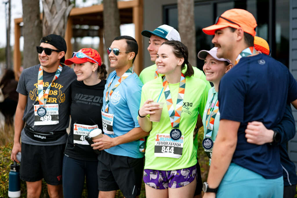 A group of runners wearing medals and race bibs pose together outdoors after completing a race in the vibrant Wildlight Yulee Florida community.