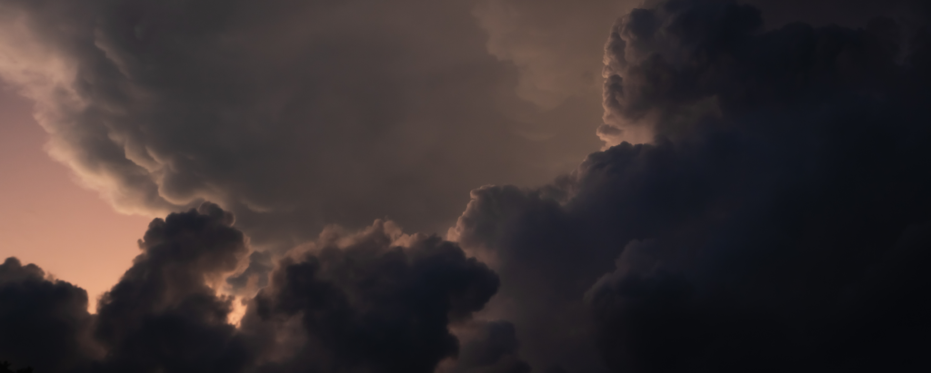 Dark storm clouds fill the sky above Wildlight Florida, with a faint light shining through, creating a dramatic and moody atmosphere over this vibrant master planned community.