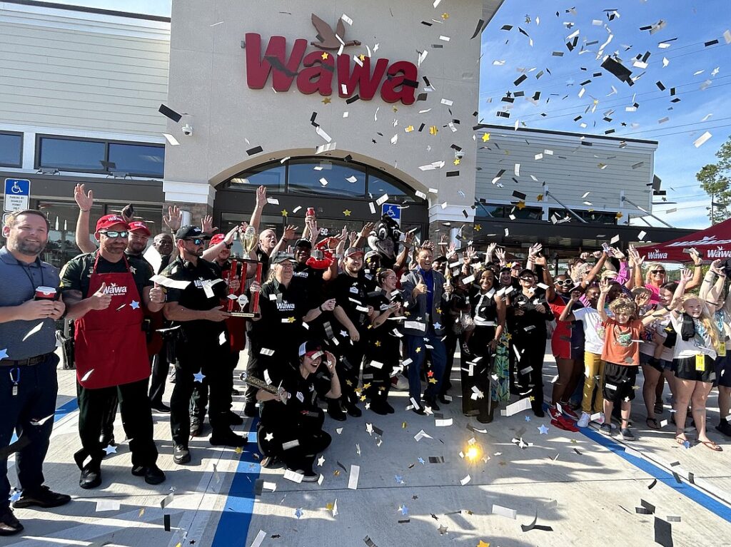 A crowd celebrates with confetti outside a Wawa store in the Wildlight Yulee Florida community, as employees and local residents pose for a cheerful group photo near the entrance.