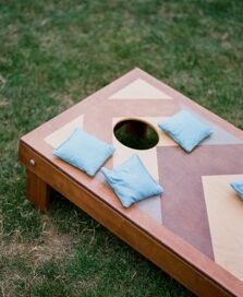 A cornhole game board with four light blue bean bags resting on green grass, perfect for outdoor fun in the vibrant Wildlight Yulee Florida community.